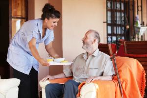 caregiver gives food to elderly man